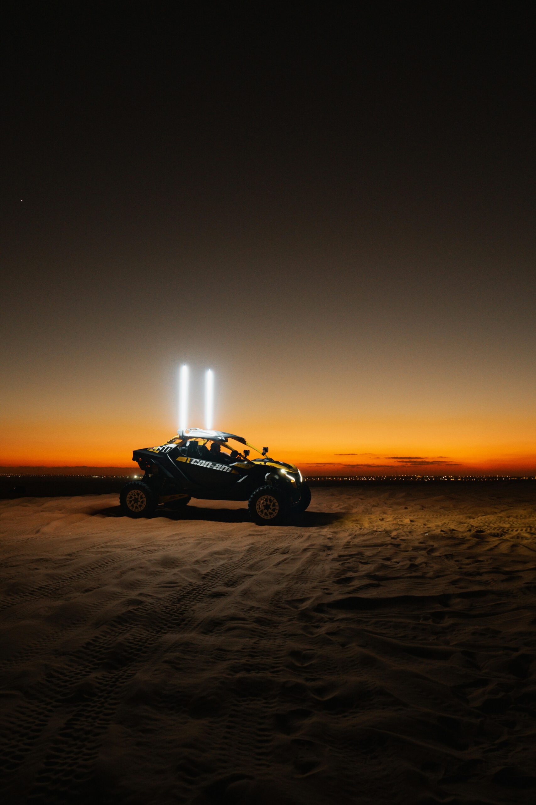 An off-road vehicle illuminated against a stunning sunset in the Dubai desert.