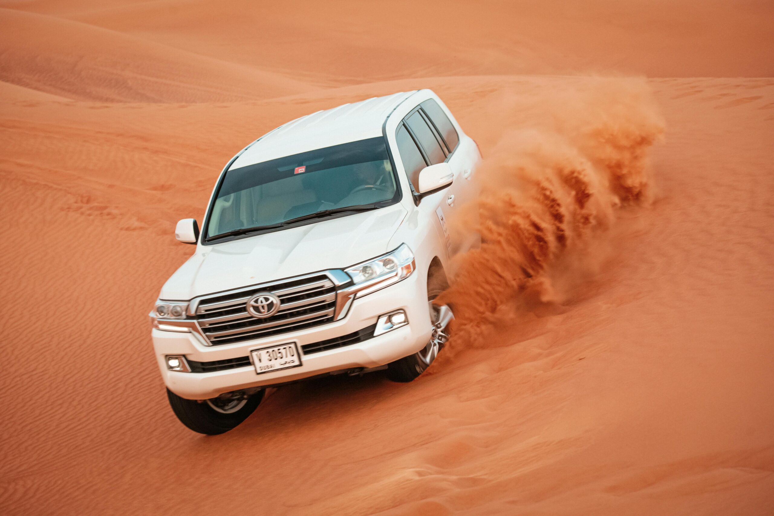 A Toyota Land Cruiser navigates the sand dunes of Dubai, showcasing its off-road capabilities.